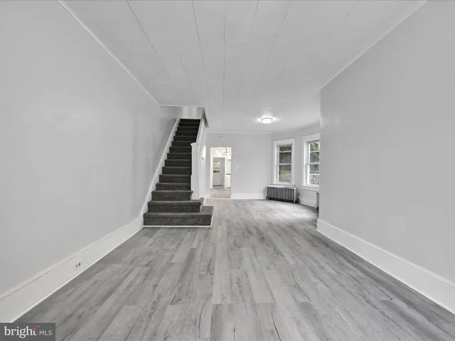 a view of an empty room with wooden floor and stairs