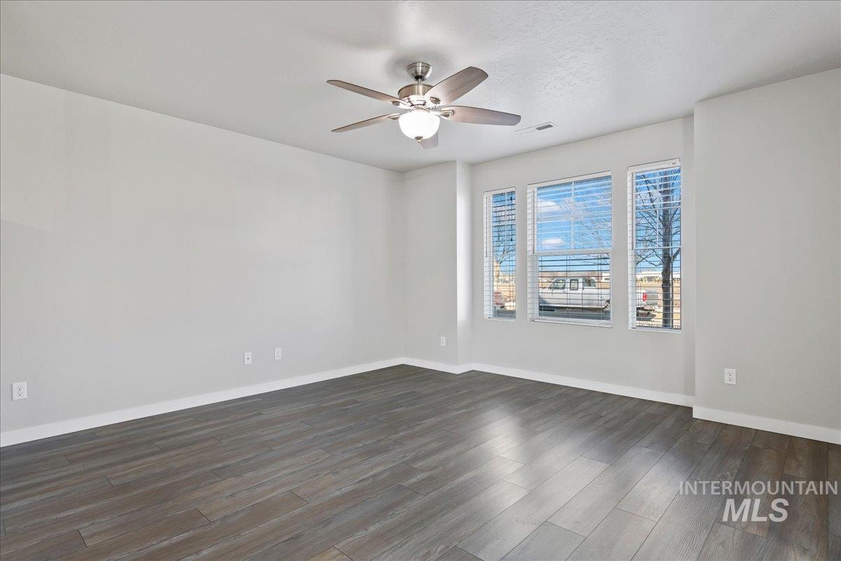 2487 East Goldstone Street Meridian, ID 83642 - Photo 4 of 25 Empty room featuring dark wood-type flooring and a ceiling fan