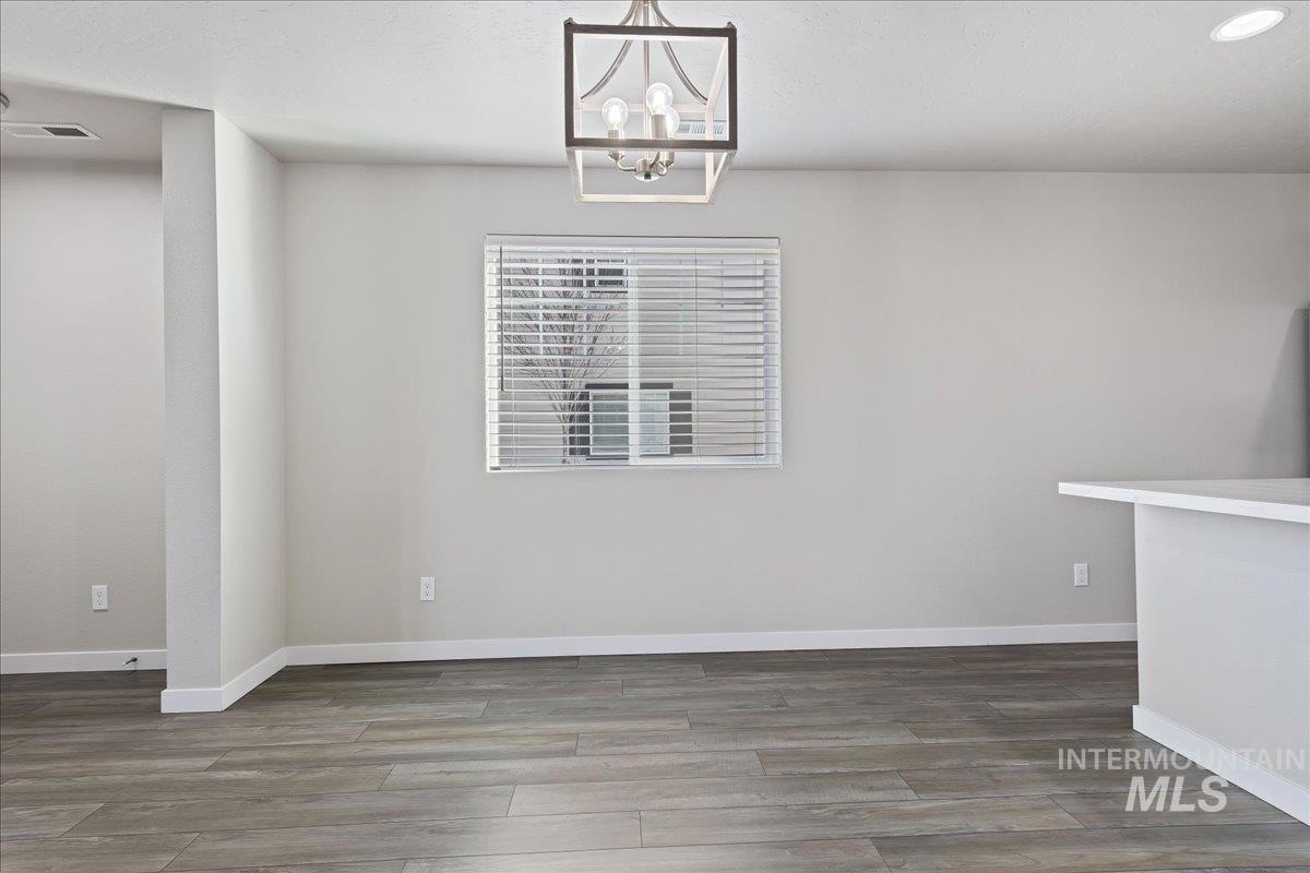 2487 East Goldstone Street Meridian, ID 83642 - Photo 7 of 25 Unfurnished dining area featuring wood finished floors and a chandelier