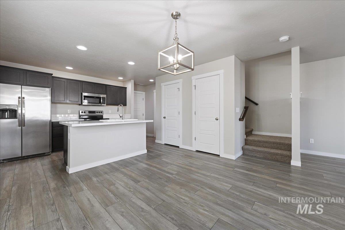 2487 East Goldstone Street Meridian, ID 83642 - Photo 23 of 25 Kitchen with stainless steel appliances, a kitchen island with sink, open floor plan, hanging lights, and light wood finished floors