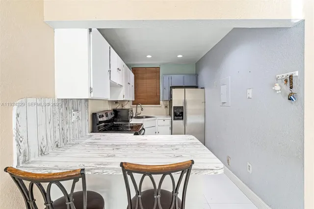 a kitchen with stainless steel appliances granite countertop a refrigerator a stove a sink a dining table and chairs