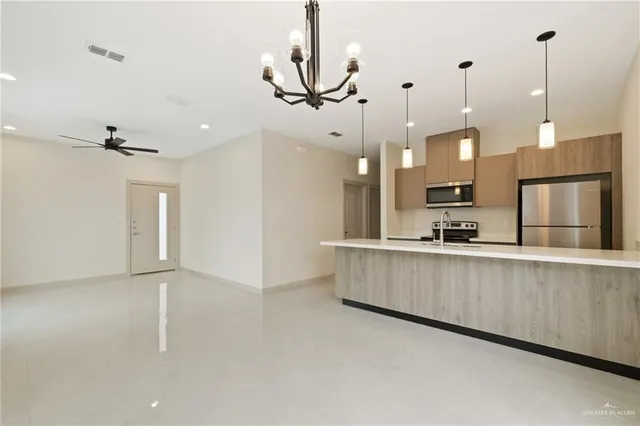 a kitchen with stainless steel appliances kitchen island wooden cabinets and chandelier