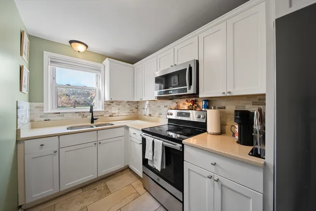 a kitchen with cabinets stainless steel appliances and a window
