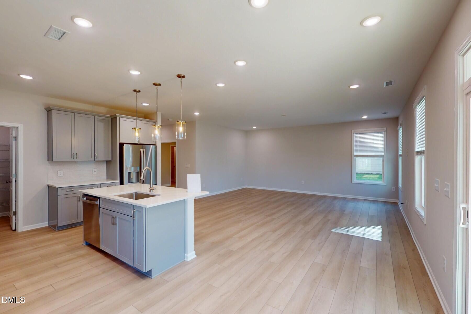109 Tawny Slope Court, Unit 13 Raleigh, NC 27603 - Photo 14 of 48 a open kitchen with kitchen island a sink dishwasher a stove and a refrigerator with wooden floor