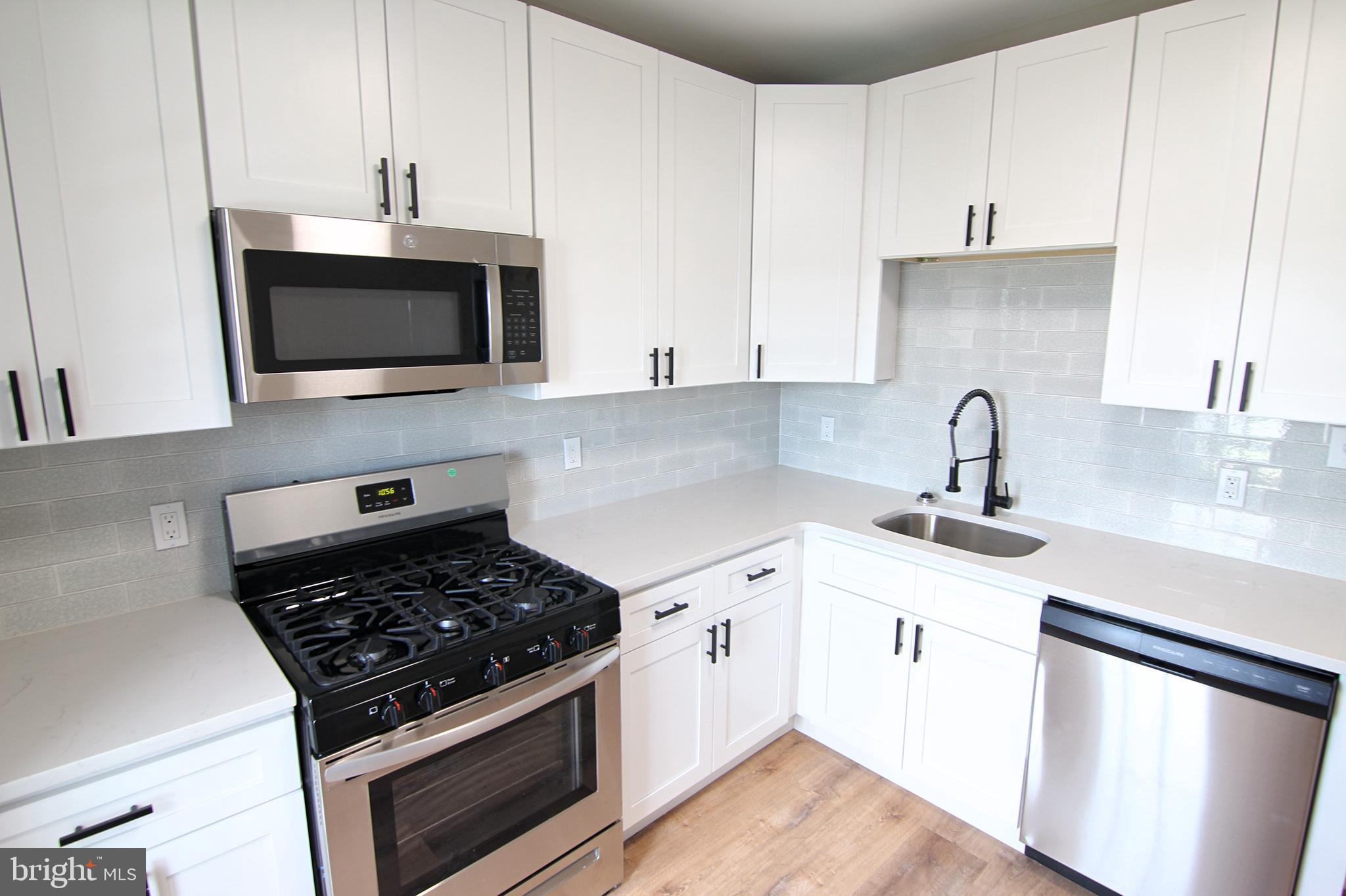 37 Sixth Street, Unit 2 Bridgeport, PA 19405 - Photo 2 of 14 a kitchen with granite countertop a sink stove and microwave