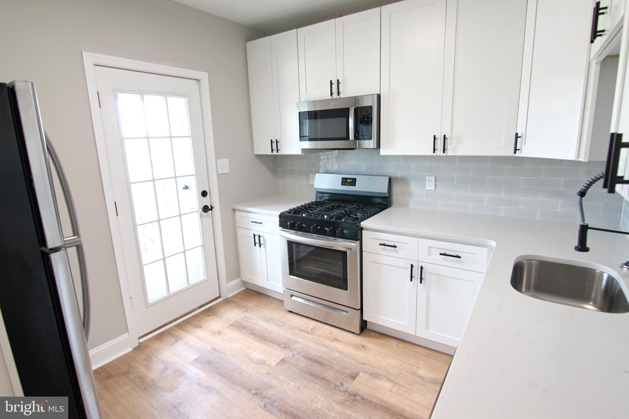 37 Sixth Street, Unit 2 Bridgeport, PA 19405 - Photo 4 of 14 a kitchen with granite countertop a stove a sink and a microwave