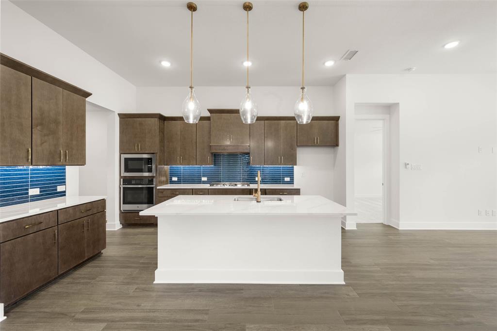2223 Shady Elm Road Midlothian, TX 76065 - Photo 6 of 27 a large kitchen with stainless steel appliances kitchen island a large counter top and a wooden floors