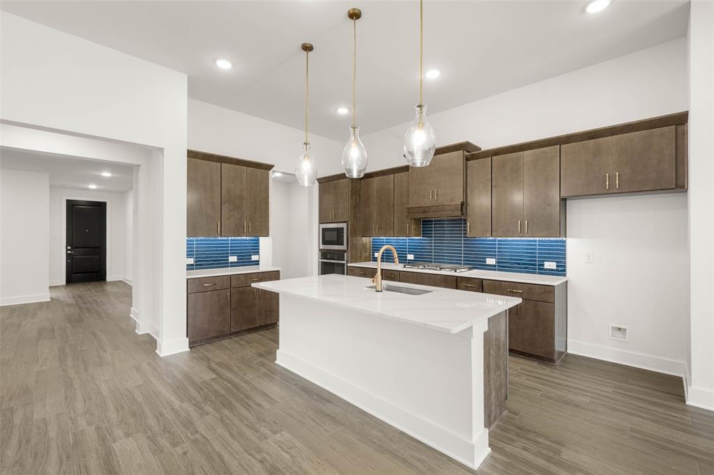 2223 Shady Elm Road Midlothian, TX 76065 - Photo 7 of 27 a large kitchen with kitchen island a stove a sink a refrigerator and a dining table with wooden floor