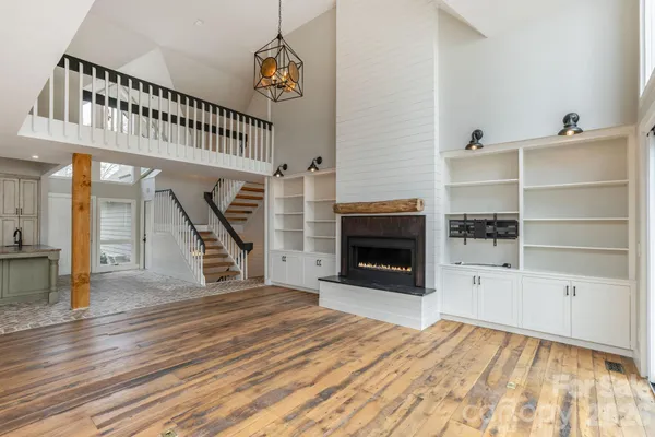 a view of an empty room with wooden floor fireplace and staircase