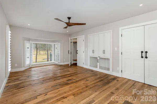 a view of empty room with wooden floor and fan