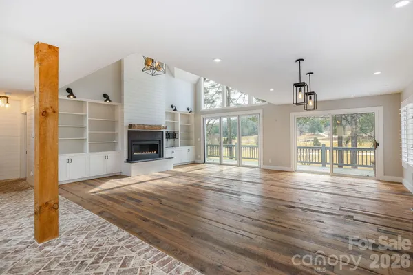 a view of an empty room with wooden floor and a fireplace