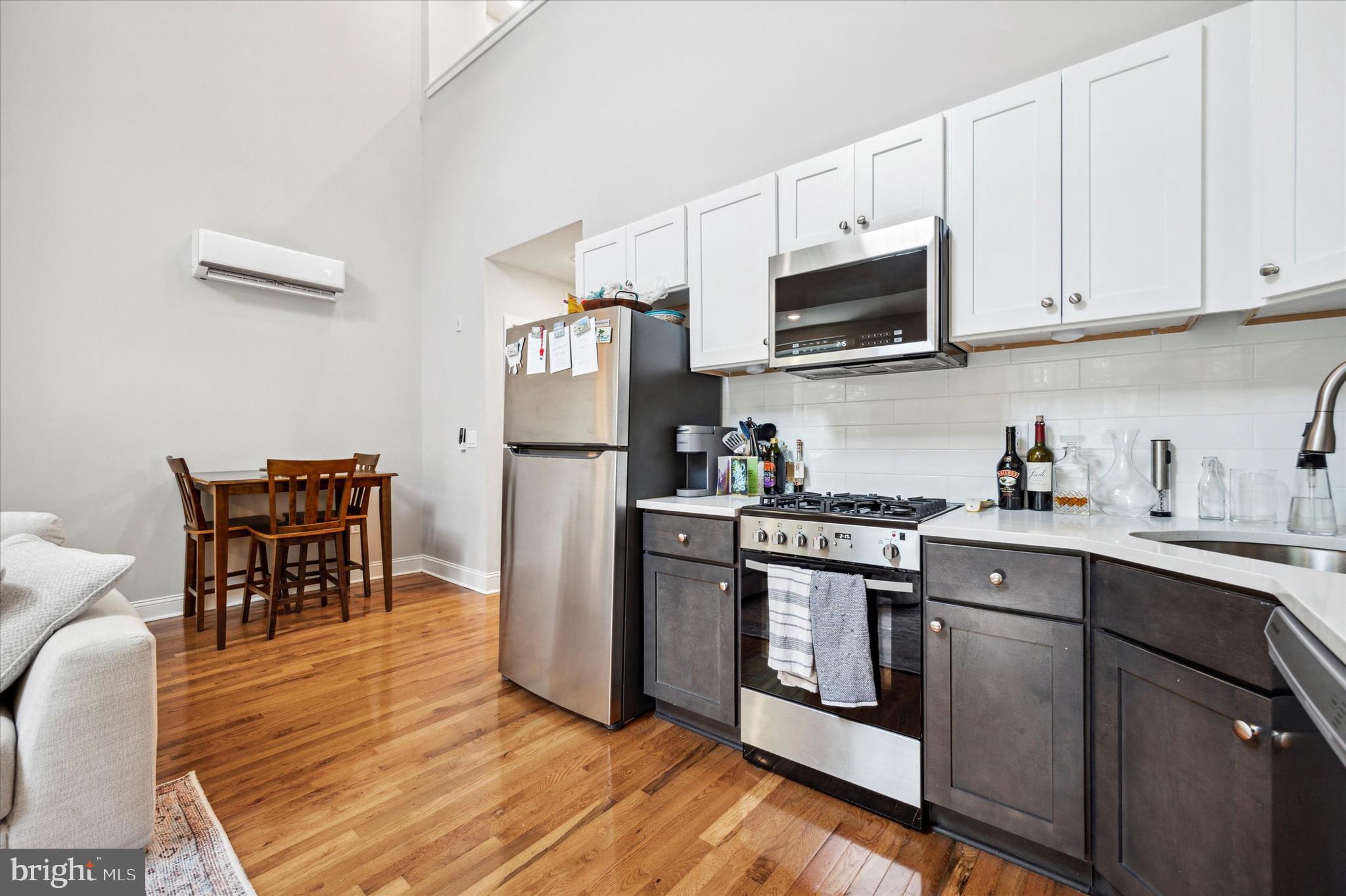 1015 Clinton Street, Unit 3 Philadelphia, PA 19107 - Photo 5 of 25 a kitchen with stainless steel appliances granite countertop a stove top oven a sink dishwasher a refrigerator and a dining table with wooden cabinet