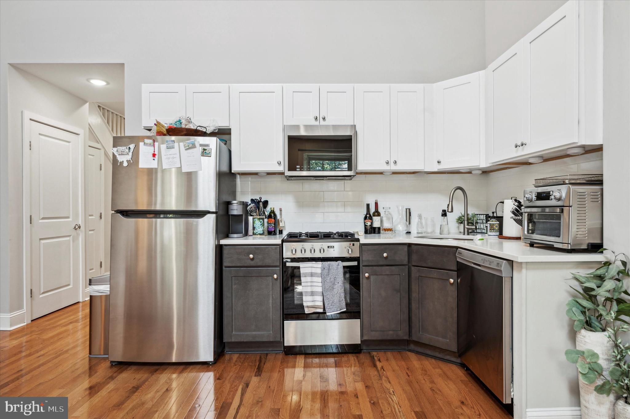 1015 Clinton Street, Unit 3 Philadelphia, PA 19107 - Photo 7 of 25 a kitchen with stainless steel appliances granite countertop a refrigerator stove a sink and dishwasher with wooden floor