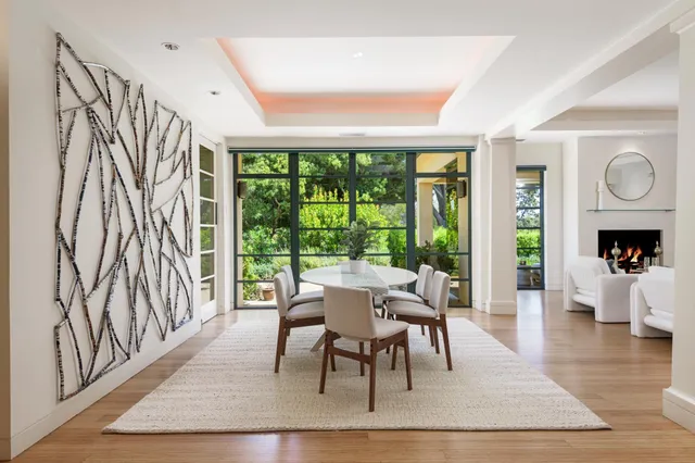 a dining room with wooden floor a rug a fireplace and a large window