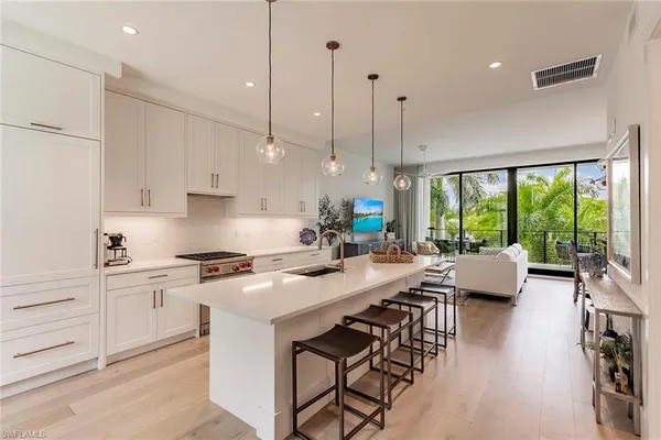 a kitchen with stainless steel appliances granite countertop a stove a sink a kitchen island with chairs and wooden floor
