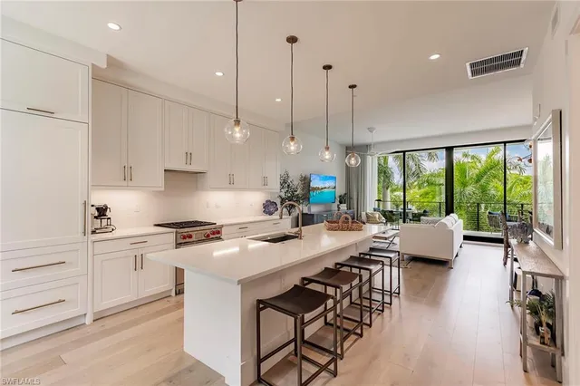 a kitchen with stainless steel appliances granite countertop a stove a sink a kitchen island with chairs and wooden floor