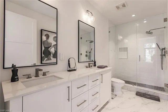 a bathroom with a double vanity sink toilet mirror and shower