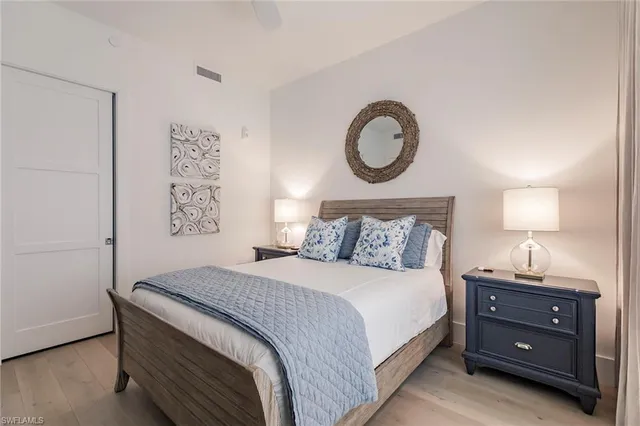 a bedroom with a bed and a lamp on dresser next to a window