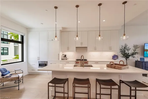 a kitchen with stainless steel appliances granite countertop a sink a stove a dining table chairs and cabinets