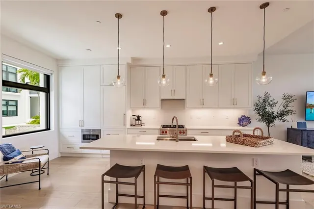 a kitchen with stainless steel appliances granite countertop a sink a stove a dining table chairs and cabinets