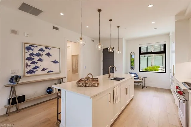 a large white kitchen with a large window a sink a center island and furniture