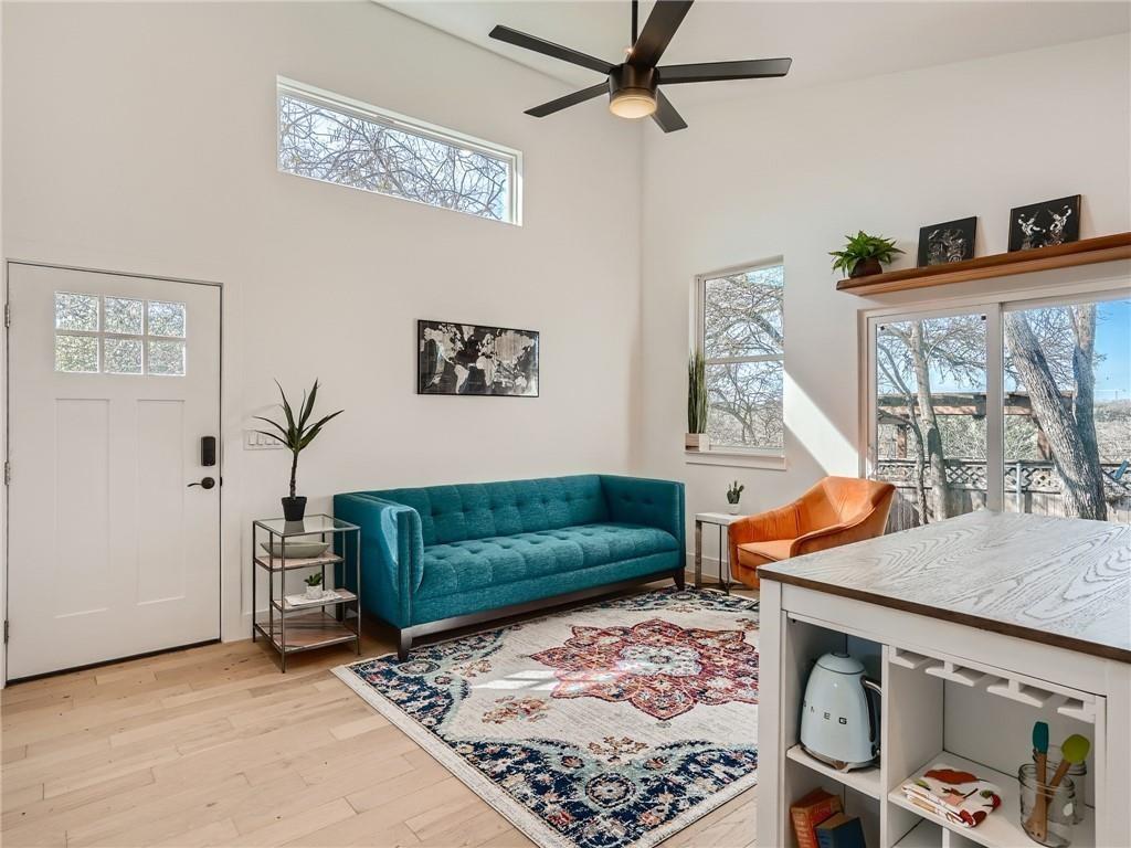 1614 Elmira Road Austin, TX 78721 - Photo 1 of 23 Living room featuring light wood finished floors, a towering ceiling, healthy amount of natural light, and a ceiling fan