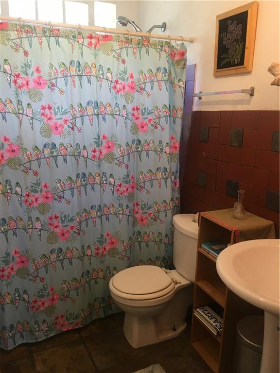 1614 Elmira Road Austin, TX 78721 - Photo 22 of 23 Bathroom featuring tile walls, a shower with shower curtain, and wainscoting