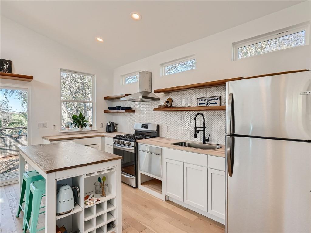 1614 Elmira Road Austin, TX 78721 - Photo 5 of 23 Kitchen with stainless steel appliances, plenty of natural light, open shelves, lofted ceiling, and recessed lighting