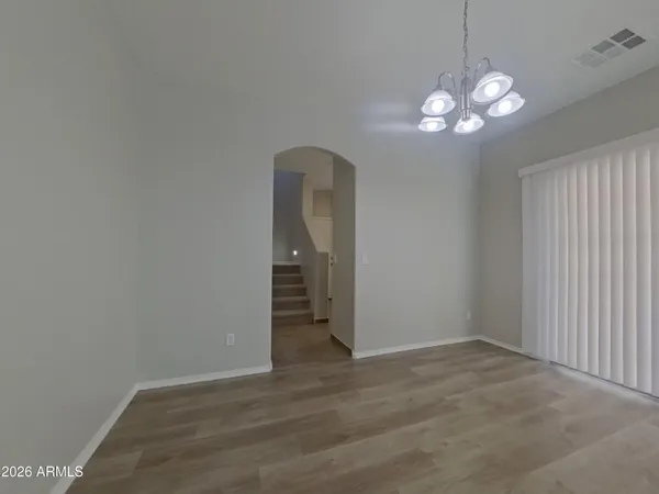 an empty room with wooden floor and chandelier