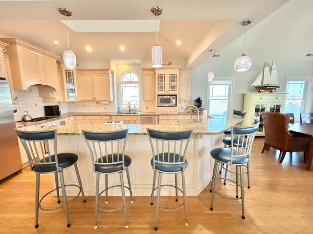 a dining area with stainless steel appliances kitchen island granite countertop a dining table chairs and a refrigerator