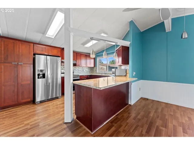 a kitchen with stainless steel appliances granite countertop a refrigerator a sink and wooden cabinets