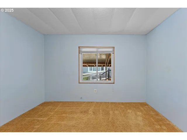 a view of an empty room with chandelier fan and windows