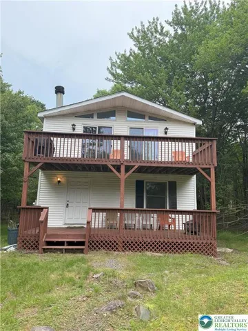 a view of a house with furniture deck and a yard