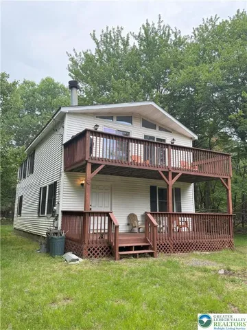 a view of a house with a yard and a wooden deck