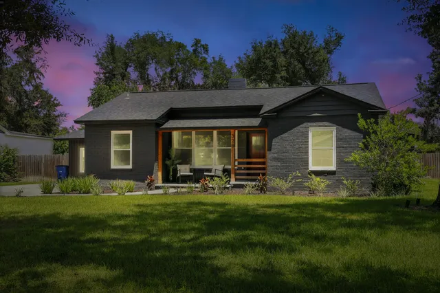 a front view of a house with a garden and trees