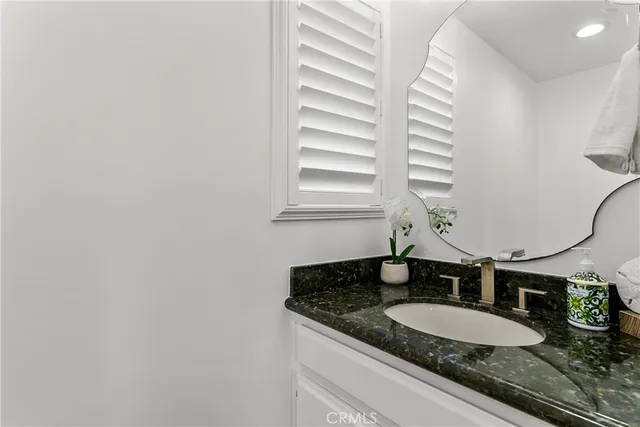 a bathroom with a granite countertop sink and a mirror