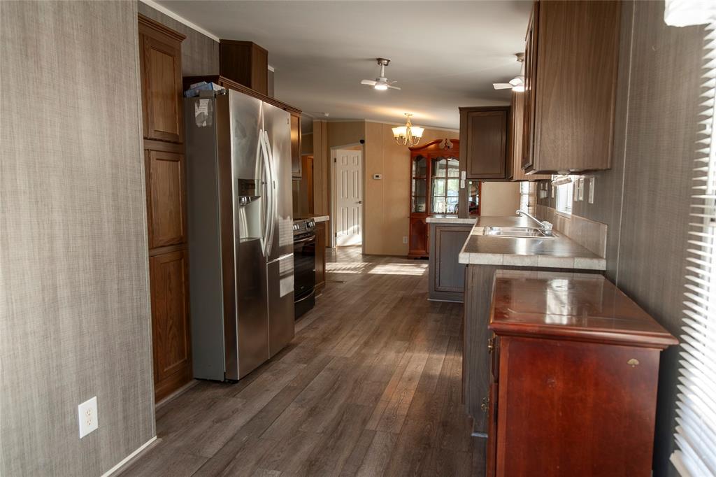 112 Southeast Front Street, Unit A Bailey, TX 75452 - Photo 23 of 39 Kitchen with tile counters, stainless steel refrigerator with ice dispenser, wallpapered walls, black range, and suspended lighting