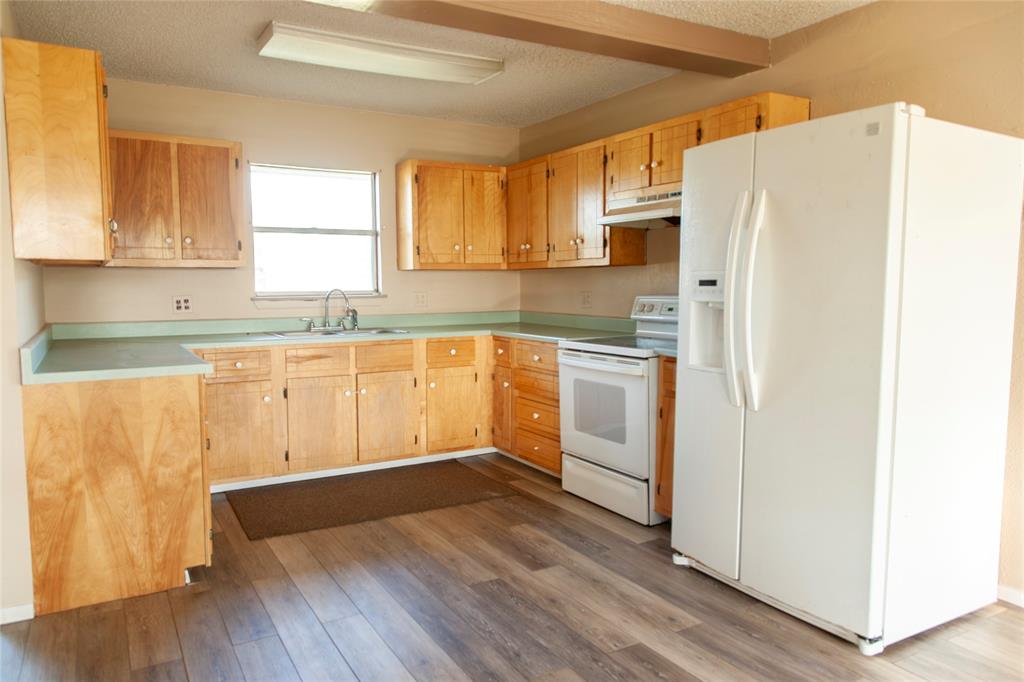 112 Southeast Front Street, Unit A Bailey, TX 75452 - Photo 6 of 39 Kitchen with white appliances, light countertops, dark wood-style flooring, a textured ceiling, and light wood finish cabinetry