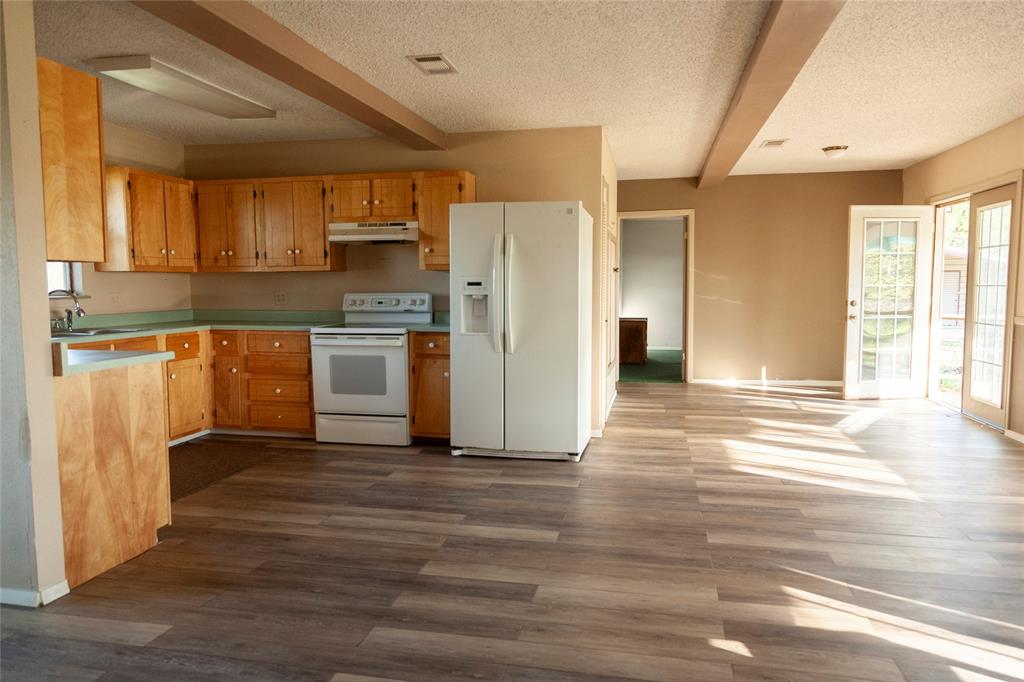 112 Southeast Front Street, Unit A Bailey, TX 75452 - Photo 7 of 39 Kitchen featuring plenty of natural light, white appliances, beam ceiling, a textured ceiling, and dark wood finished floors