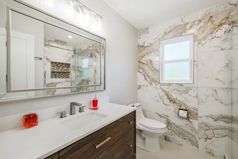 a bathroom with a sink vanity mirror and toilet