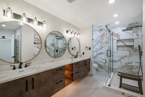 a bathroom with a double vanity sink mirror and shower