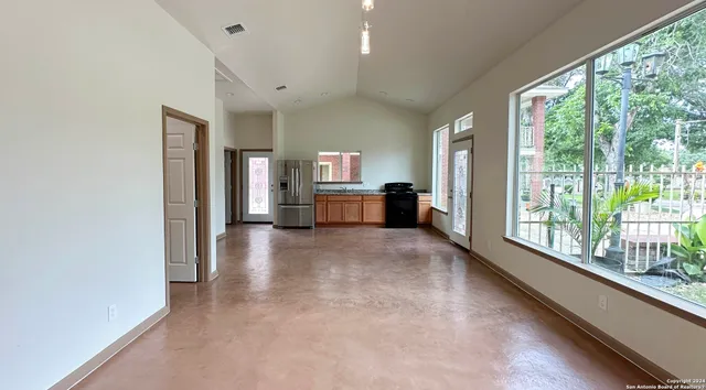 a view of an empty room with a kitchen and a window