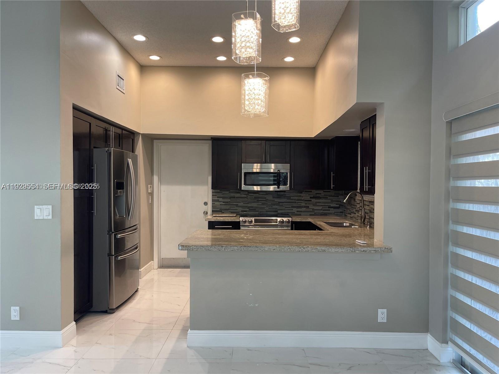 10101 Northwest 5th Street, Unit 10101 Plantation, FL 33324 - Photo 5 of 29 a large kitchen with stainless steel appliances kitchen island a large counter top and oven