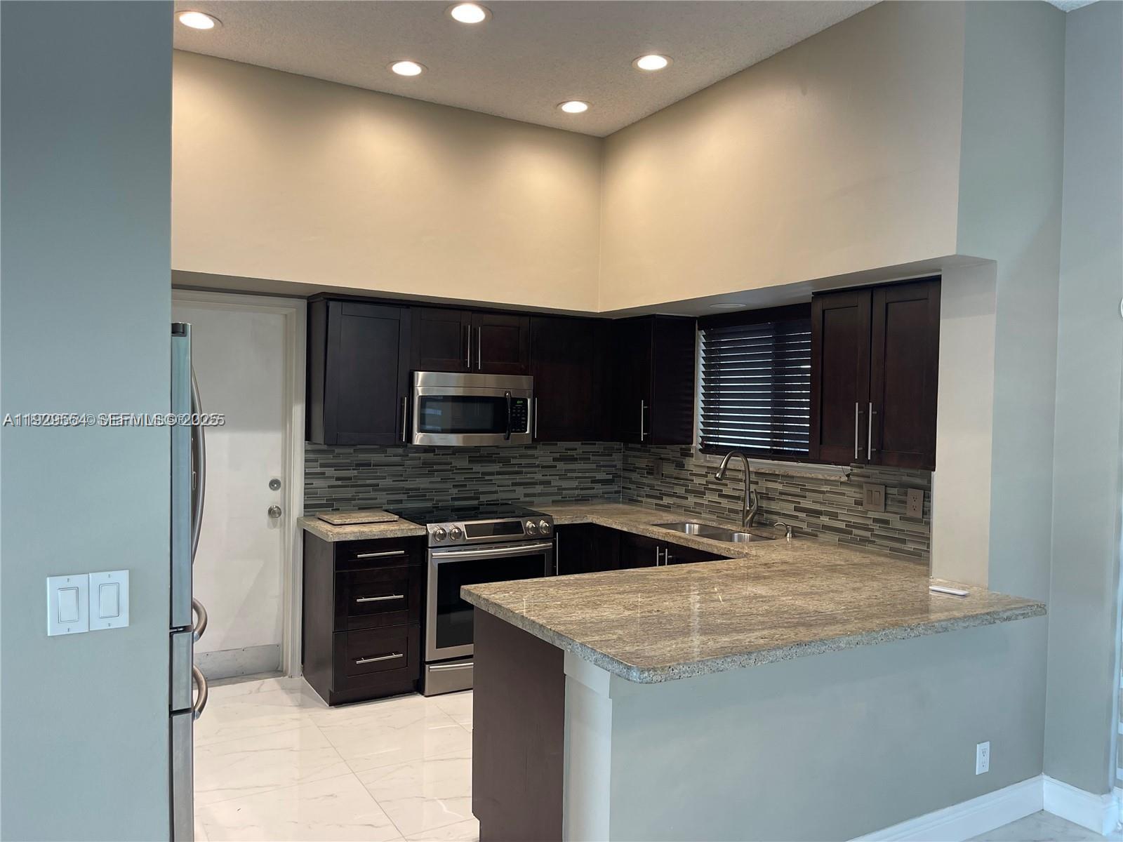 10101 Northwest 5th Street, Unit 10101 Plantation, FL 33324 - Photo 6 of 29 a kitchen with stainless steel appliances granite countertop a sink and a stove