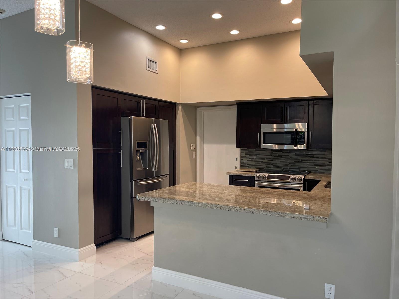 10101 Northwest 5th Street, Unit 10101 Plantation, FL 33324 - Photo 7 of 29 a kitchen with stainless steel appliances a refrigerator and a stove top oven