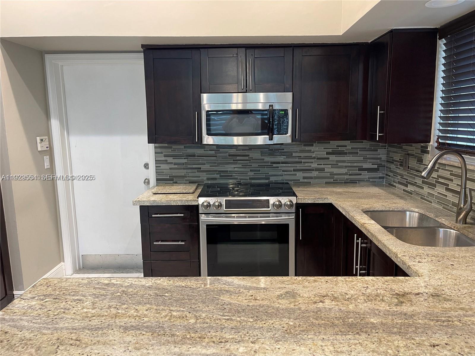 10101 Northwest 5th Street, Unit 10101 Plantation, FL 33324 - Photo 9 of 29 a kitchen with stainless steel appliances granite countertop a stove a sink and a microwave