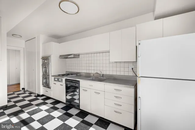 a kitchen with a checkered floor and white cabinets