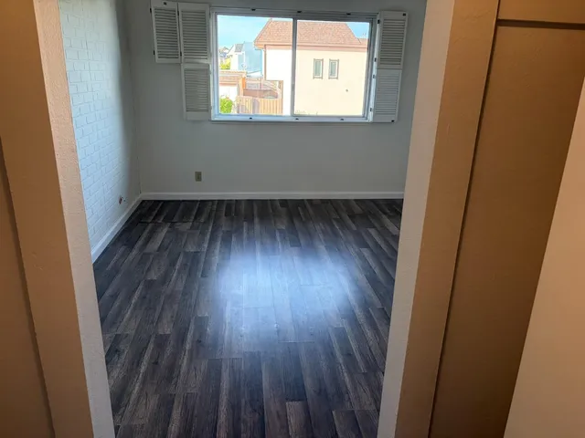 an empty room with wooden floor and windows