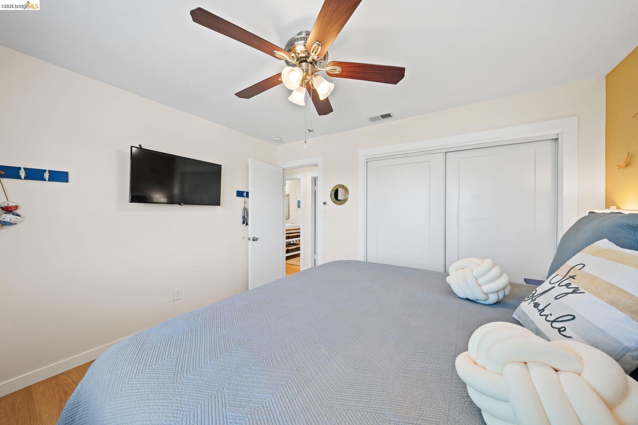 1704 Taylor Road Bethel Island, CA 94511 - Photo 36 of 73 Bedroom featuring wood-finish flooring, a ceiling fan with integrated lighting, and a double-door closet with white sliding doors