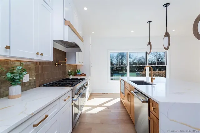 a kitchen with stainless steel appliances a sink a stove and a wooden floor